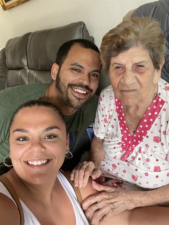 Three family members share a warm moment together in a cozy living room during a visit.