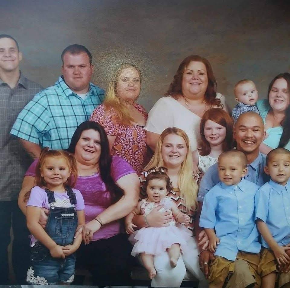 Diverse group of family members smiling and posing together in a studio background.