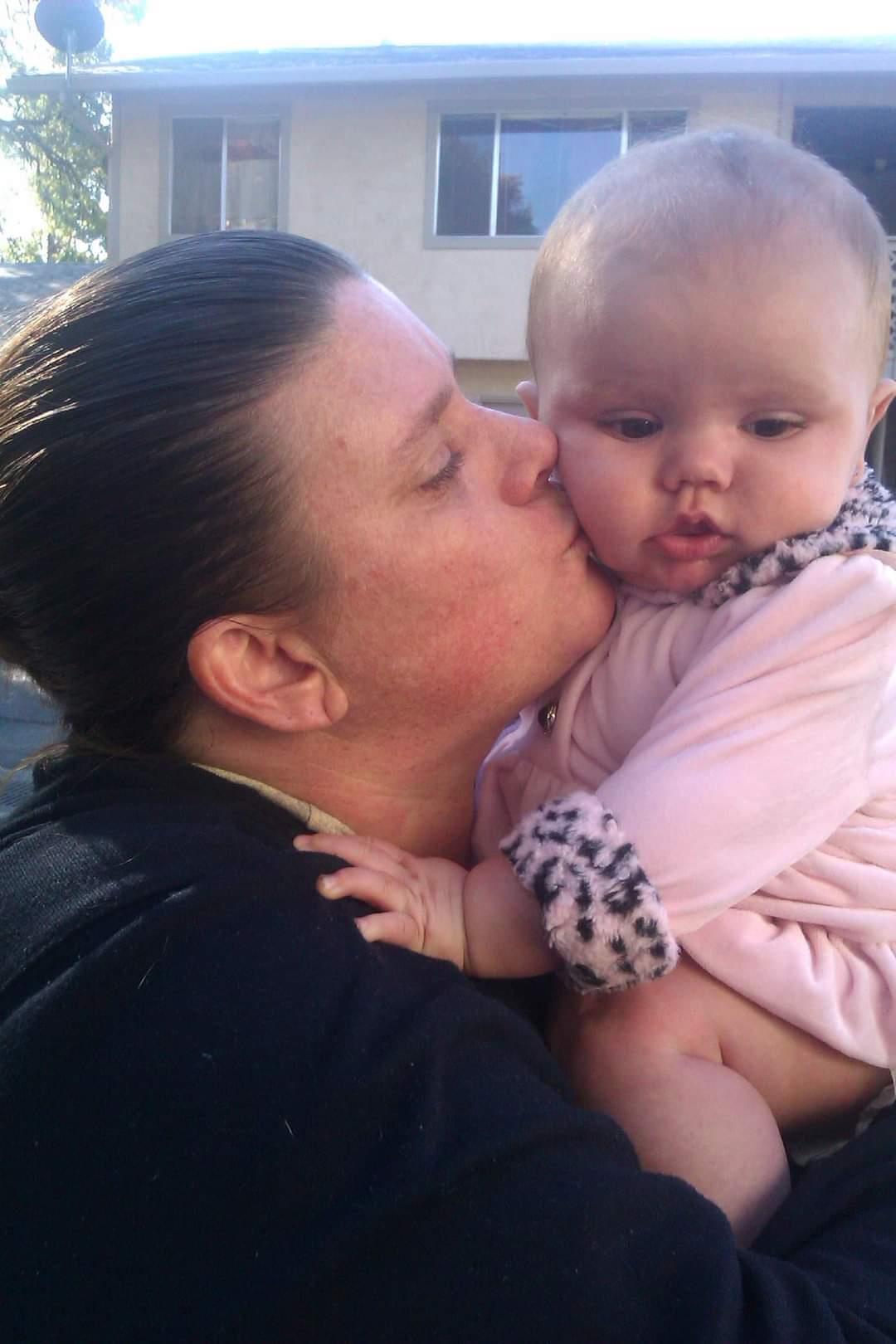 A parent lovingly kisses their baby, both smiling and enjoying a joyful moment together.