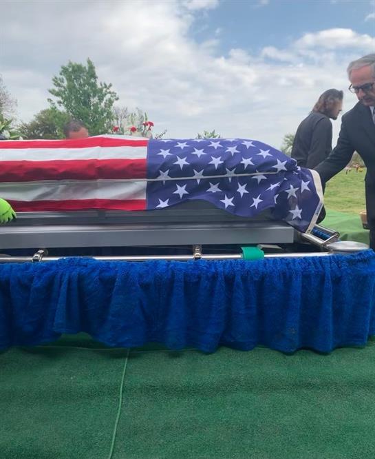 Family gathers to mourn as a flag-draped casket is lowered into the ground.