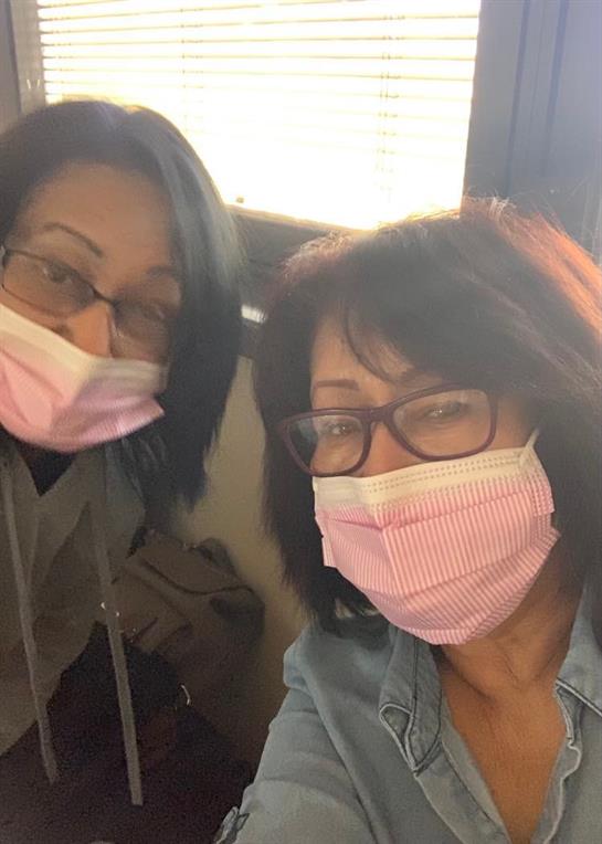 Women take a selfie while wearing masks, smiling and enjoying their time together indoors.