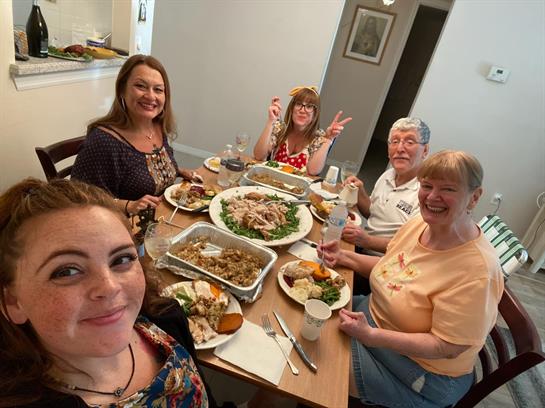 Five people share laughter and a delicious homemade meal in a cozy dining room.