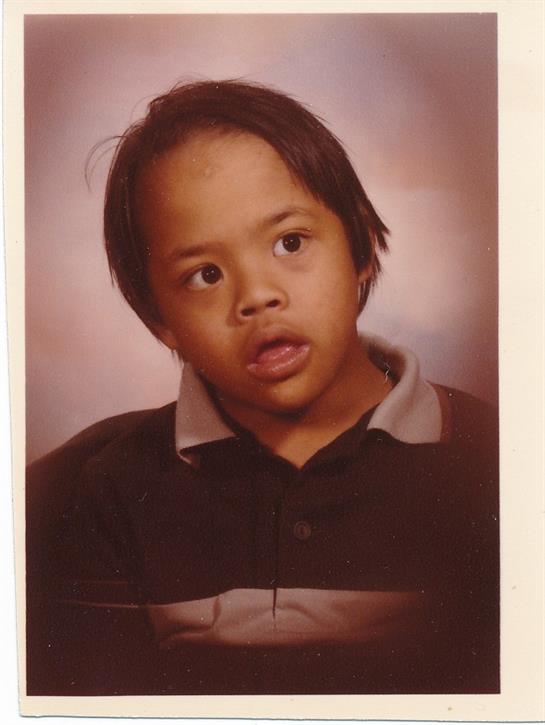 A young boy is looking surprised while posing for his school picture with a neutral background.