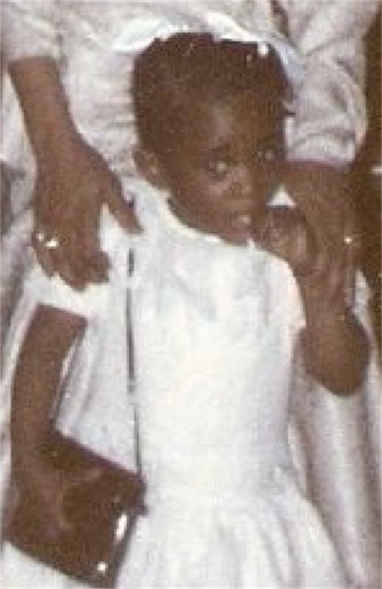 A young child in white smiles and laughs with adults at a family event.