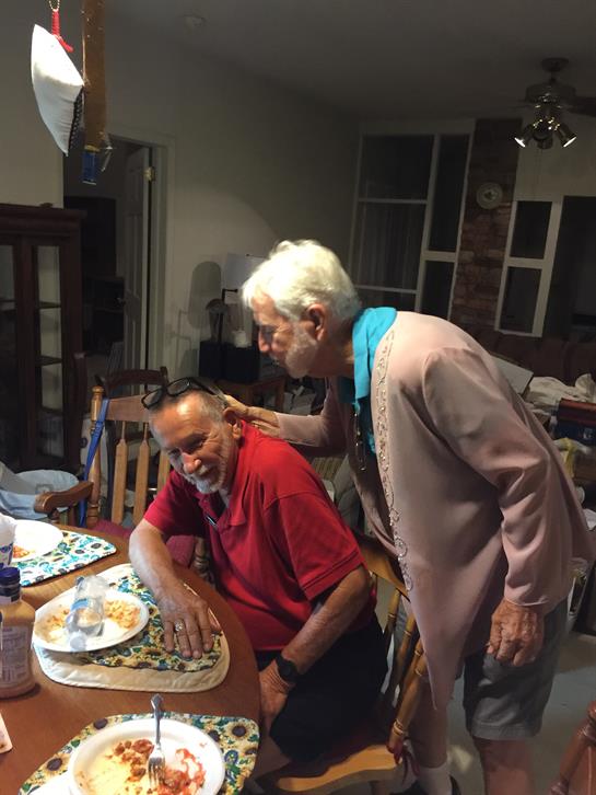A cheerful elderly woman enjoys time at home with a man in a red shirt.