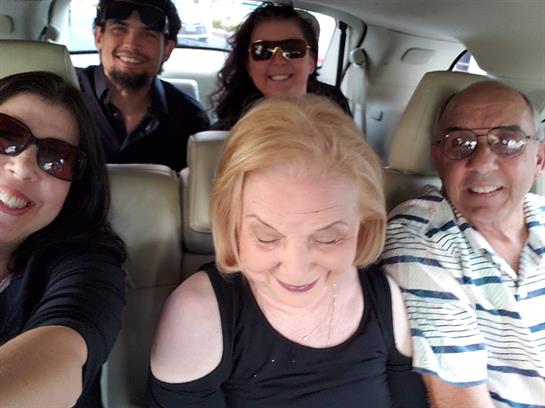 Five friends are gathered in a car, sharing smiles and laughter on a sunny day.