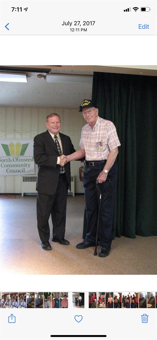 Two men shake hands in a community center, celebrating veterans' contributions to society.