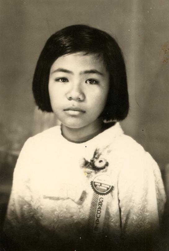 A girl with short hair dressed in a vintage outfit gives a serious look while posing.