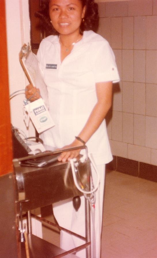 Nurse operates medical device in hospital corridor while attending to patient needs.