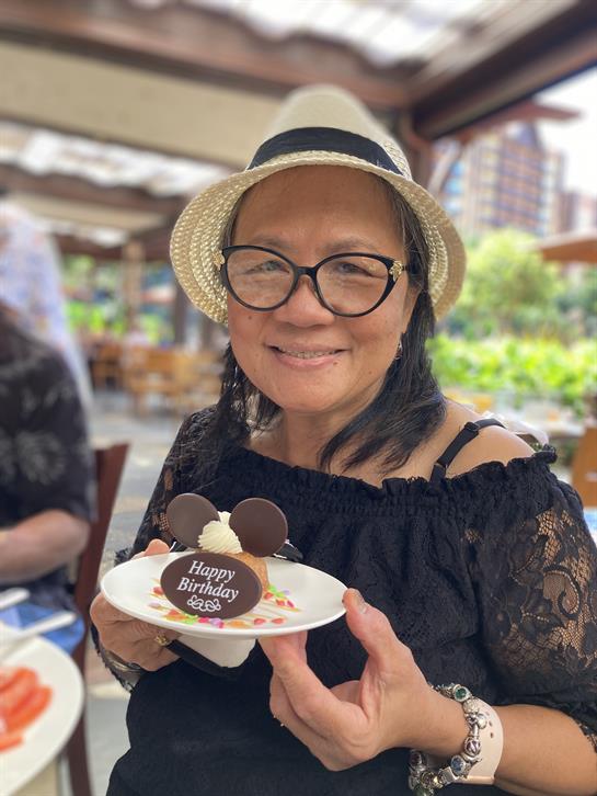 A woman celebrates her birthday with friends, enjoying a chocolate dessert in a cozy space.