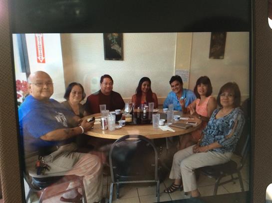 A group of friends sits around a table sharing food and laughter in a welcoming restaurant setting.