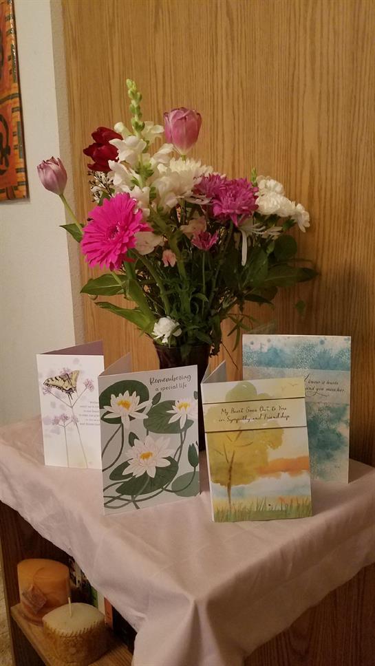 A vibrant bouquet of flowers sits with beautifully illustrated greeting cards on a table.