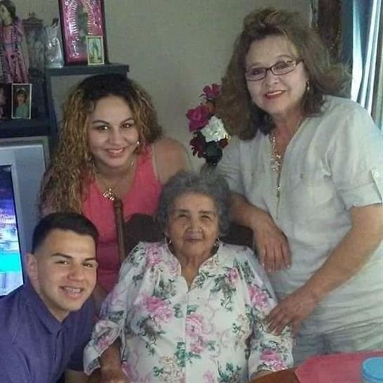 Four family members smile around their grandmother, celebrating her joyful birthday together.