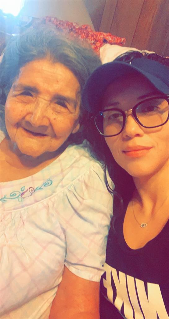 A young woman and her grandmother share smiles while enjoying each other's company at home.