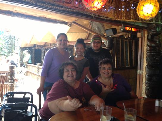 Several friends smile and pose together at a restaurant while enjoying their time indoors.