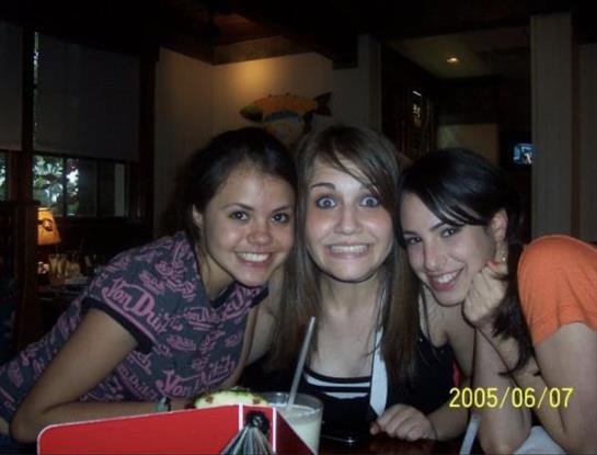 Friends smile widely while sharing drinks at a relaxed social setting in the evening.