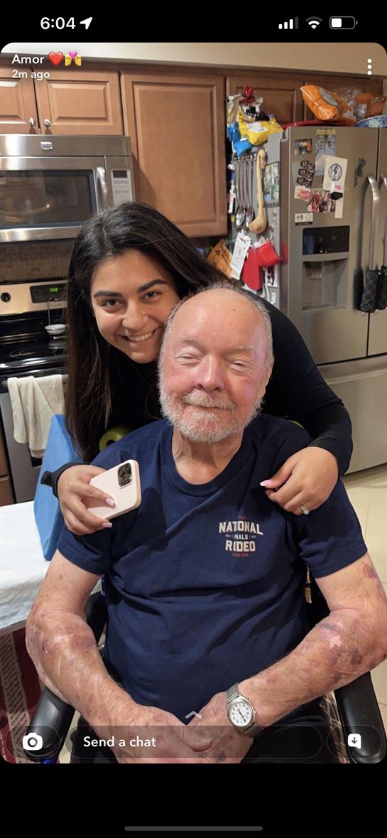 Granddaughter and grandfather smile together in the kitchen during a heartwarming family visit.