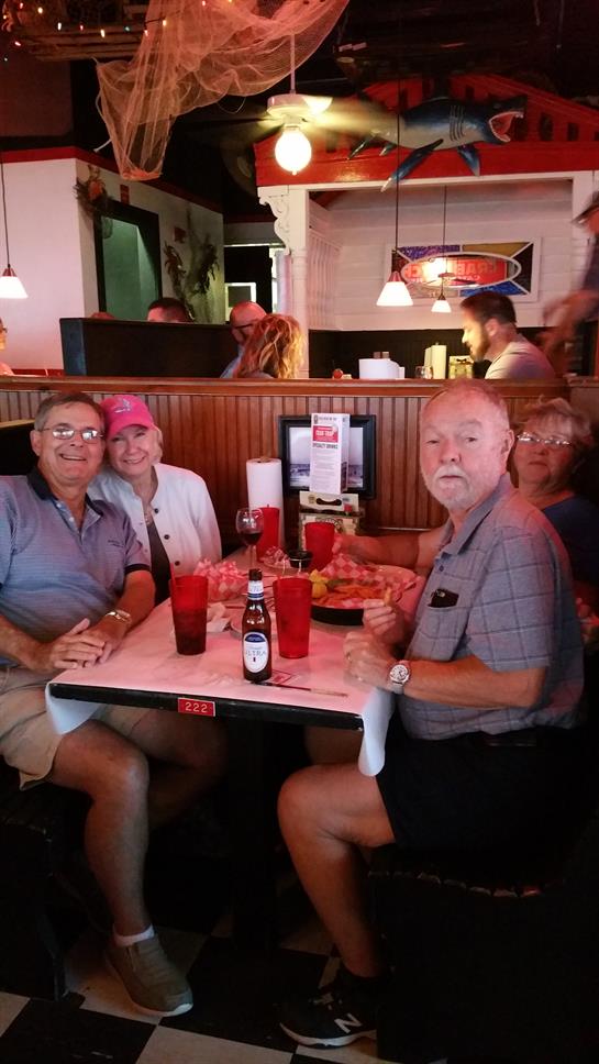 Four seniors gather at a table sharing laughs and their meals in a bustling restaurant atmosphere.