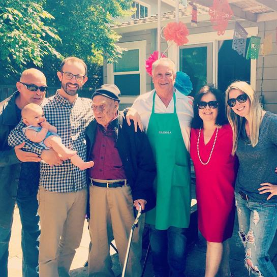 A joyful family reunion takes place in a sunny backyard with colorful decorations and laughter.