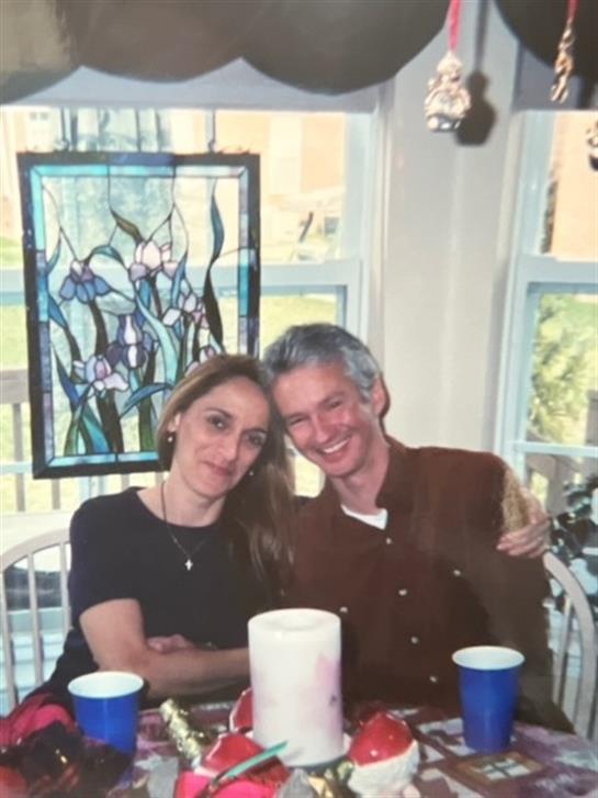 A pair of individuals smiles warmly while sitting at a table adorned with various drinks.
