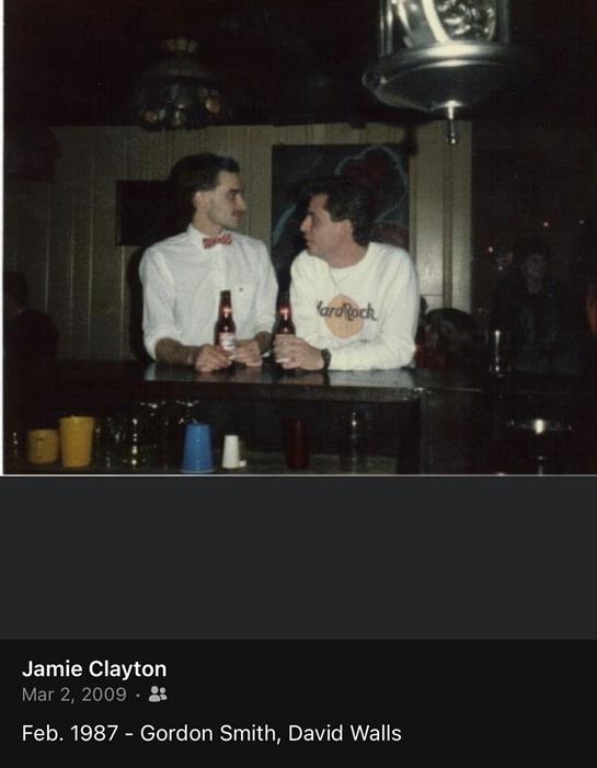 Friends share laughter and drinks at a busy bar while engaging in lively conversation at night.