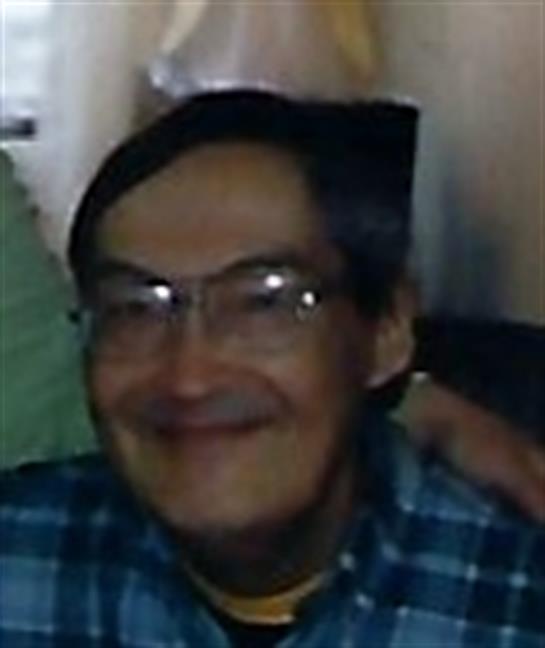 A smiling elderly man with glasses enjoys a cozy gathering with friends.