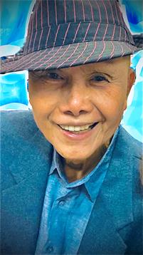 An elderly man showcases a warm smile while wearing a hat, celebrating at a lively event.