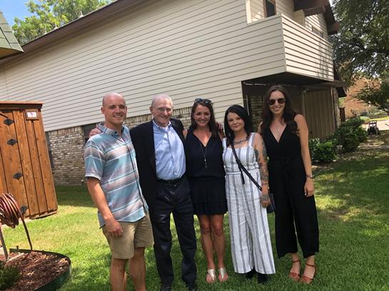 Friends and family smile together in a warm atmosphere during a summer gathering in a backyard.