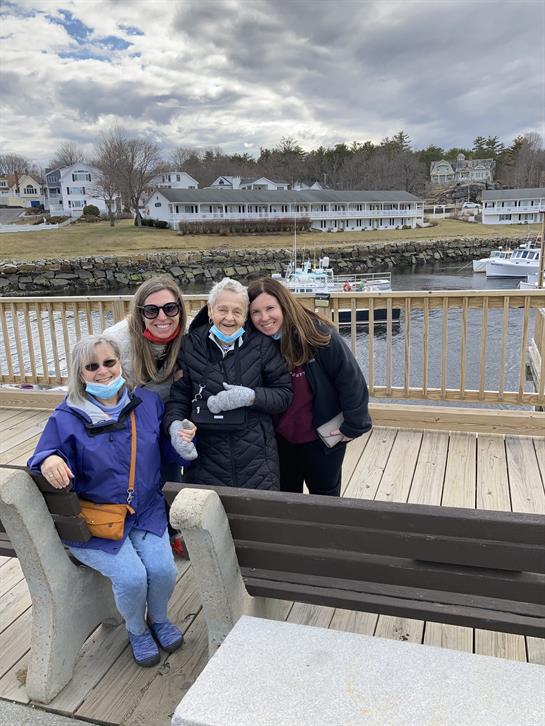 Four family members enjoy a joyful moment together on a pier overlooking a harbor.