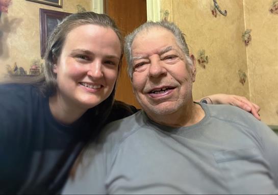A woman and an older man are happily posing together, enjoying each other's company at home.