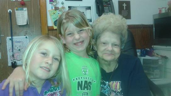 Three family members, including two children and their grandmother, smiling warmly together.