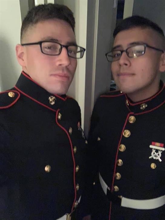 Two young men dressed in military formal uniforms smile for a picture at a special gathering.