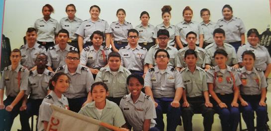 Enthusiastic cadets pose together in uniforms, showcasing teamwork and camaraderie in their program.
