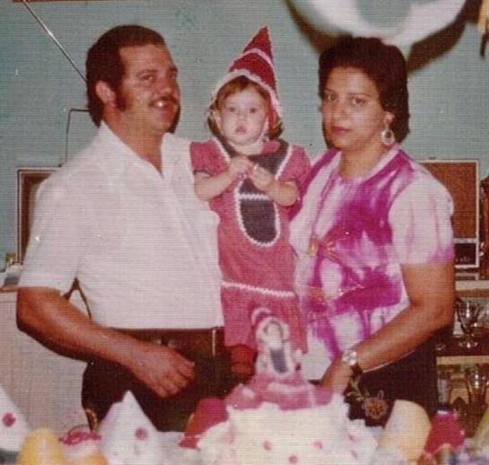 A family celebrates a joyful child in a festive outfit at a birthday party.