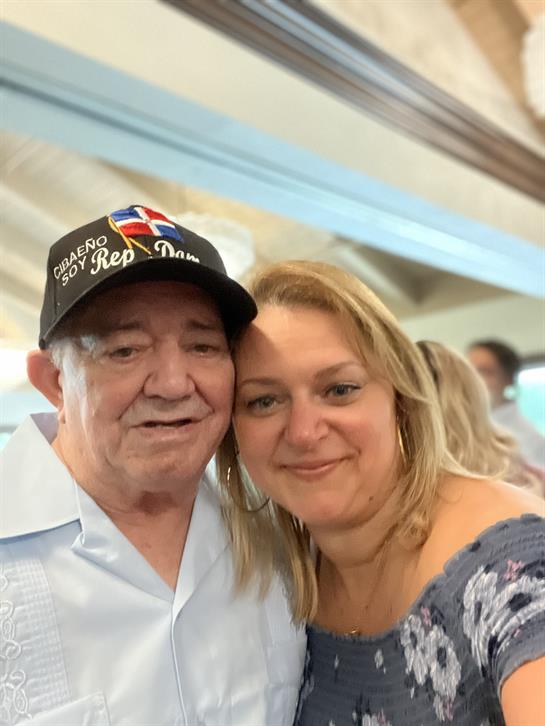 Two friends pose joyfully for a photo at a community celebration, surrounded by others.
