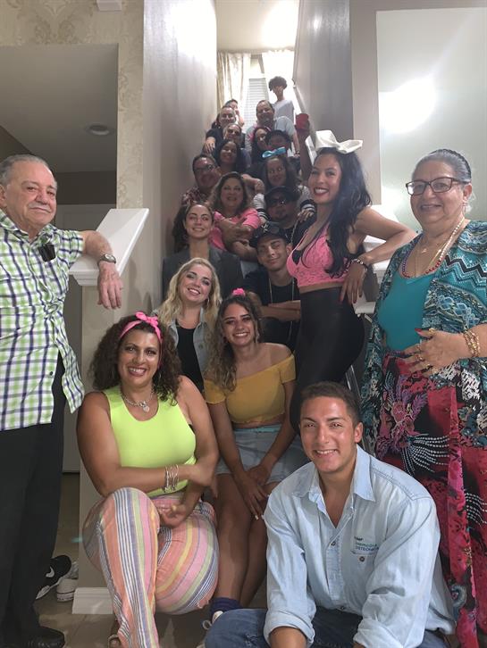 A lively group enjoys a cheerful reunion on the staircase, showcasing smiles and vibrant attire.