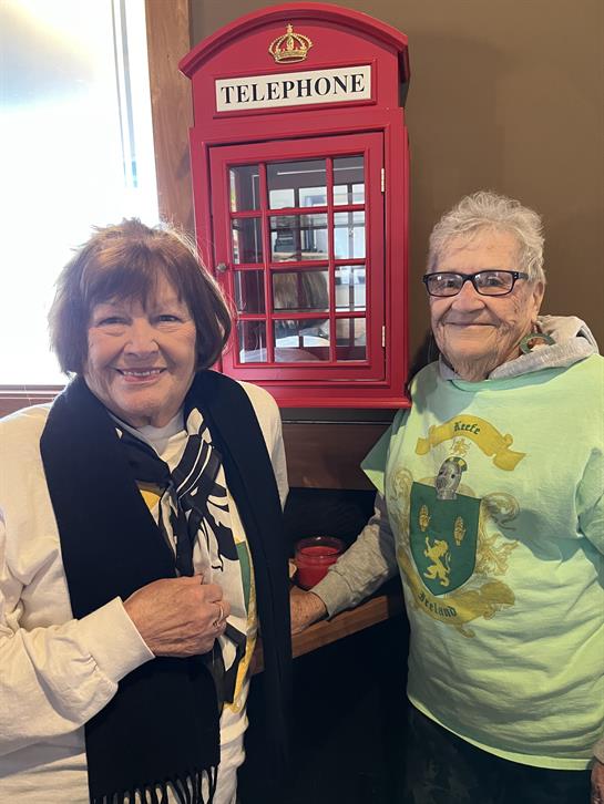 Two elderly women share a joyful moment together, enjoying their time at a cafe.