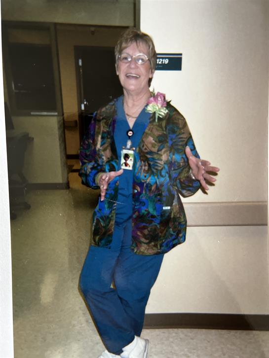 A healthcare worker stands joyfully in a hospital corridor, celebrating a special moment.