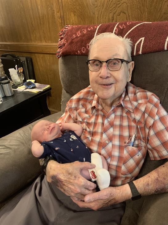 An elderly man joyfully holds a newborn baby in his arms, showcasing a tender moment of bonding.