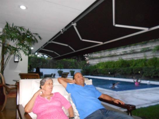 Two family members unwind on lounge chairs next to a serene pool in a cozy setting.