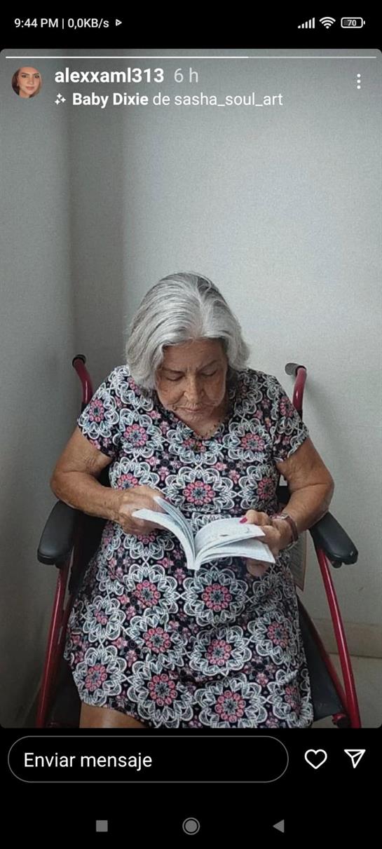 An elderly woman enjoys reading a book in a wheelchair, absorbed in her activity indoors.