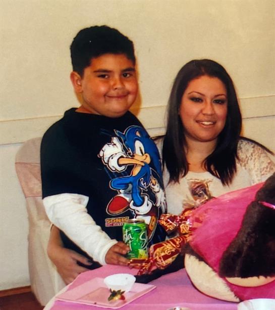 A child and an adult pose together, smiling and enjoying snacks at a family gathering.