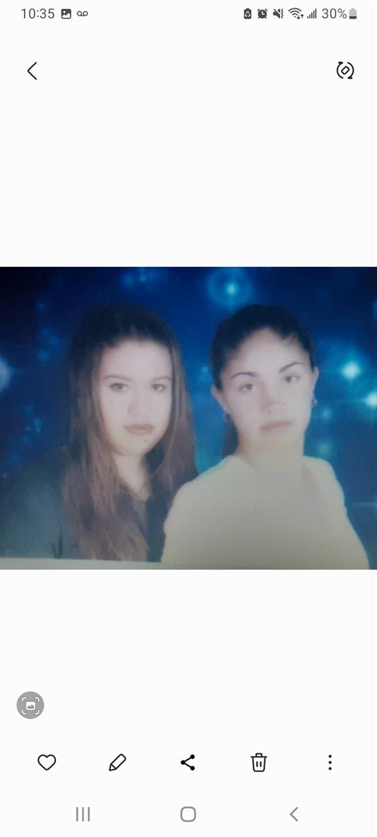 Two women stand side by side, showcasing their distinct styles and expressions under blue lighting.