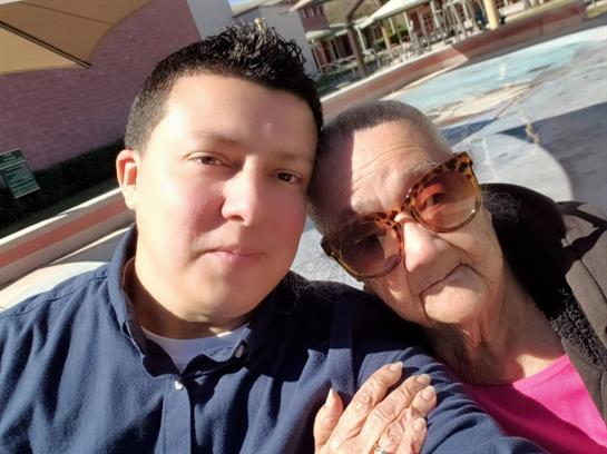 A young man and his grandmother enjoy a sunny day together outdoors.