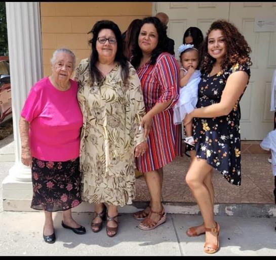 Four women of different generations pose happily outdoors, showcasing vibrant clothing and joy.