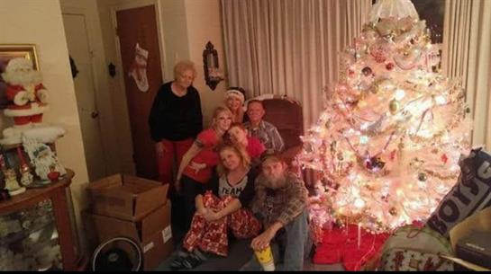 Family gathers by a glowing Christmas tree, celebrating the holiday spirit together.