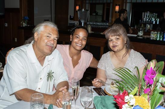 Three family members enjoy a meal together, smiling and sharing a moment at the restaurant.