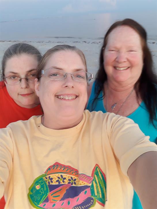 Three women take a selfie on the beach, enjoying the sunset and each other's company.