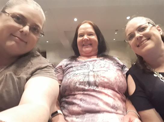 Three friends share a joyful moment at a social event, capturing their happiness and camaraderie.