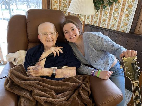 Happy grandfather and granddaughter smile together while relaxing in a cozy living room setting.